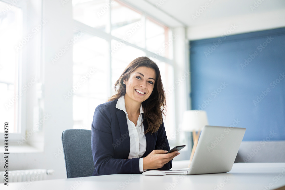 Portrait of happy businesswoman sitting at desk in the office Portrait of happy businesswoman sitting at desk in the office