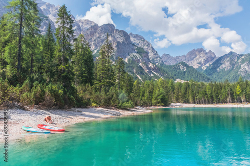 Man by paddleboards at Pragser Wildsee lakeshore on sunny day, Dolomites, Alto Adige, Italy