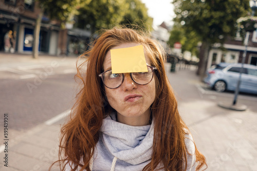 Redheaded woman with adhesive note sticking on her forehead photo