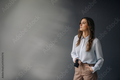 Portrait of serious young businesswoman with cell phone looking sideways photo