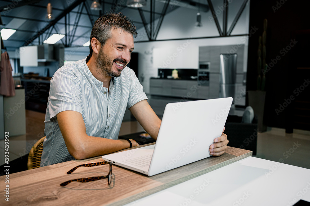 Smiling male professional looking at laptop while doing freelance work in office Smiling male professional looking at laptop while doing freelance work in office