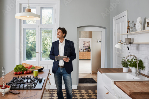 Man using tablet in kitchen looking at ceiling lamp photo