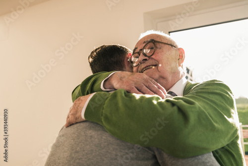 Smiling senior man hugging young man