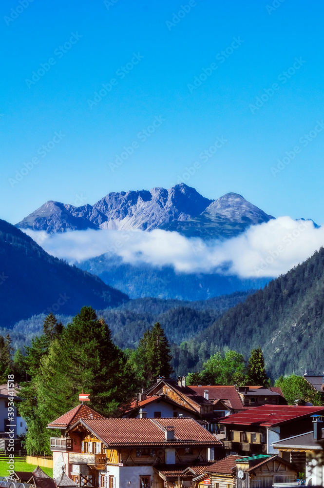 Austria, Tyrol, Ehrwald, Mountain village houses with forested valley and Zugspitze mountain in background Austria, Tyrol, Ehrwald, Mountain village houses with forested valley and Zugspitze mountain in background