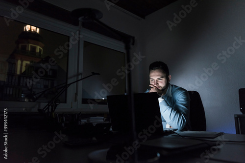 Businessman working on laptop in office at night