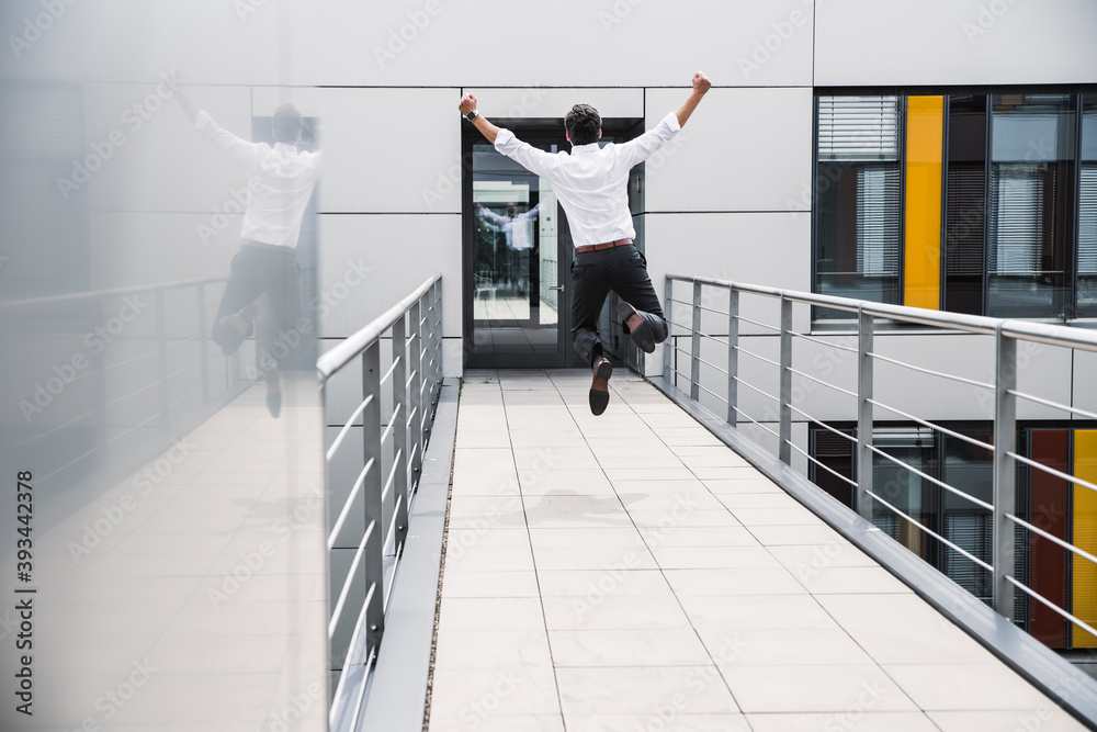 Cheering businessman jumping on skywalk at office building