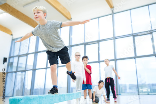 Schoolboy balancing on balance beam in gym class