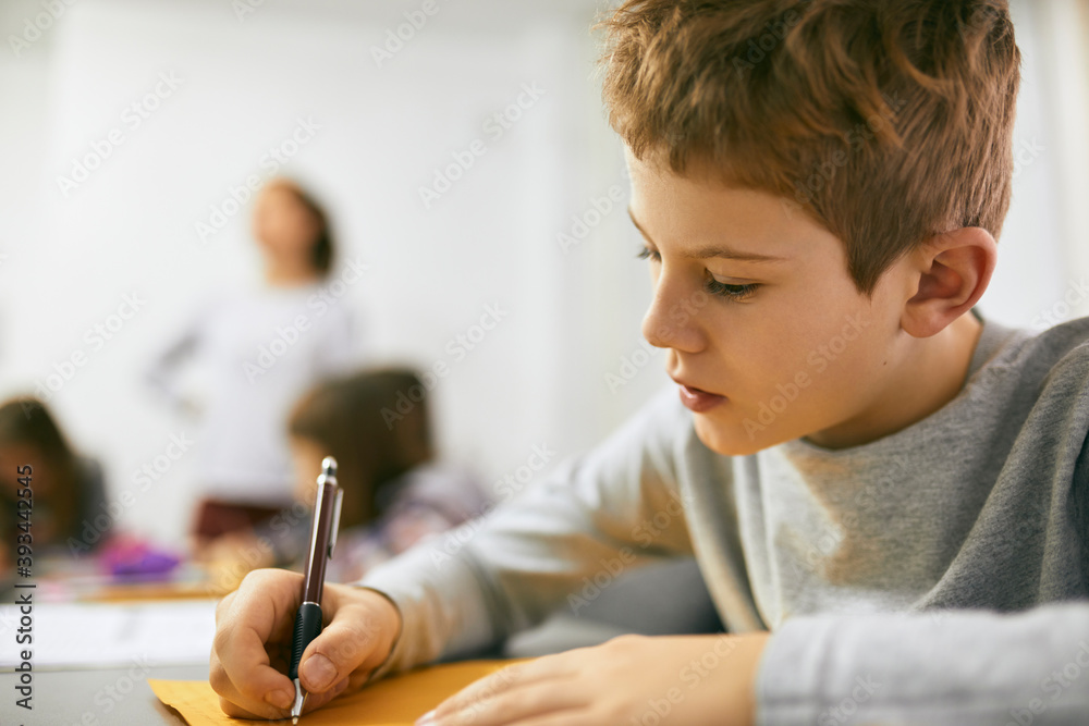 Schoolboy writing on desk in class Schoolboy writing on desk in class