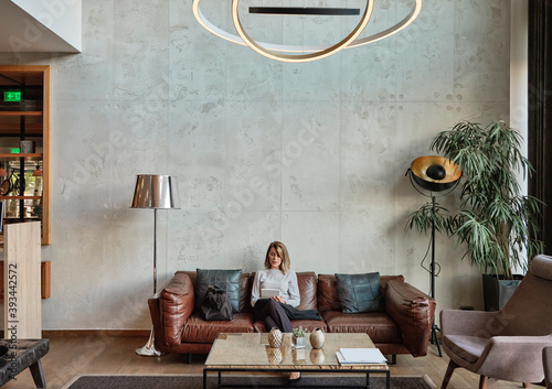 Senior woman sitting in hotel lobby while holding digital tablet photo