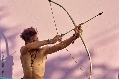 Barechested young man with bow and arrow outdoors photo