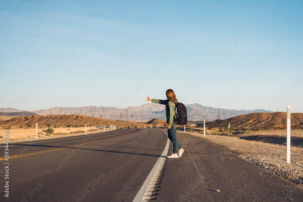 Woman hitchhiking on desert road, Nevada, USA Woman hitchhiking on desert road, Nevada, USA