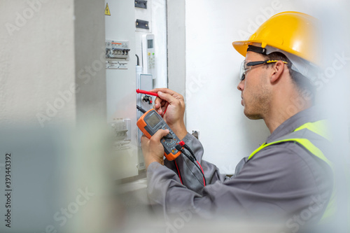 Electrician working with voltmeter at fusebox photo