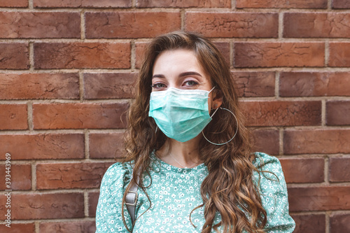Woman wearing face mask against brick wall during COVID-19 outbreak