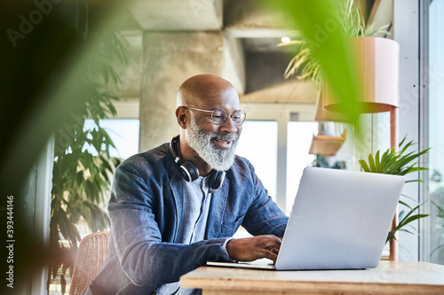 Smiling mature businessman working from home on laptop