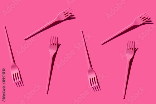 Pattern of pink plastic forks against pink background photo