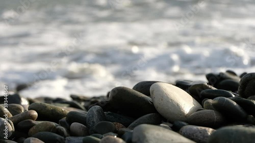 Pebbles close up in front of coming waves.