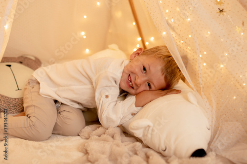 Cute little boy lying down on bed with teddy bear photo