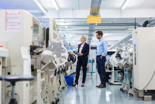 Male technician standing near businesswoman analyzing machinery at factory photo