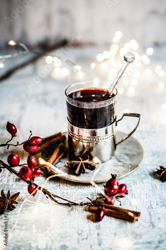 Christmas lights, rose hips and cup of mulled wine with cinnamon sticks and star anise