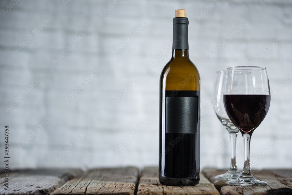 Dark bottle and glasses of expensive red wine on wooden table on white background. Concept of advertising and promotion. Space for text. Dark bottle and glasses of expensive red wine on wooden table on white background. Concept of advertising and promotion. Space for text.