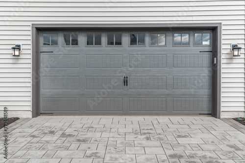 Gray two single car garage door framed with architectural stone to add accent, with transom light windows divided by muntins grills 