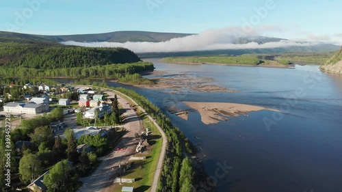 Drone aerial shot view of Dawson City in northern Canada, Yukon Territory. Gold Rush town in the summer with Yukon River, city, town and sunet over the mountains. 
