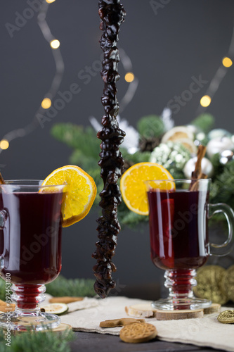 Mugs of warm wine with orange, Churchela, cookies and cinnamon, dried fruit and spruce branches, Traditional hot drink for Christmas, close-up shot of warm wine photo