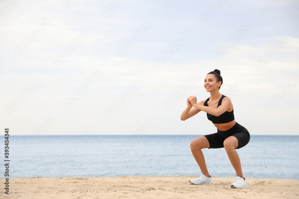 Young woman doing exercise on beach, space for text. Body training