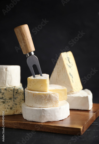 Different types of cheese and fork on black table