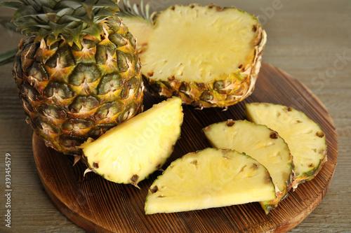 Whole and cut pineapples on wooden table, closeup
