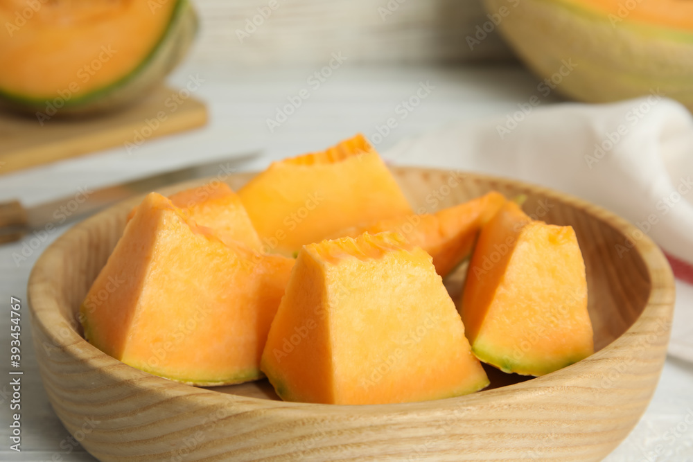 Pieces of tasty melon on wooden plate, closeup
