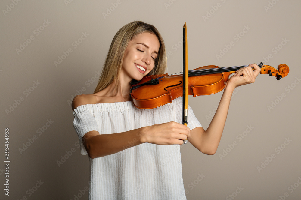 Beautiful woman playing violin on beige background