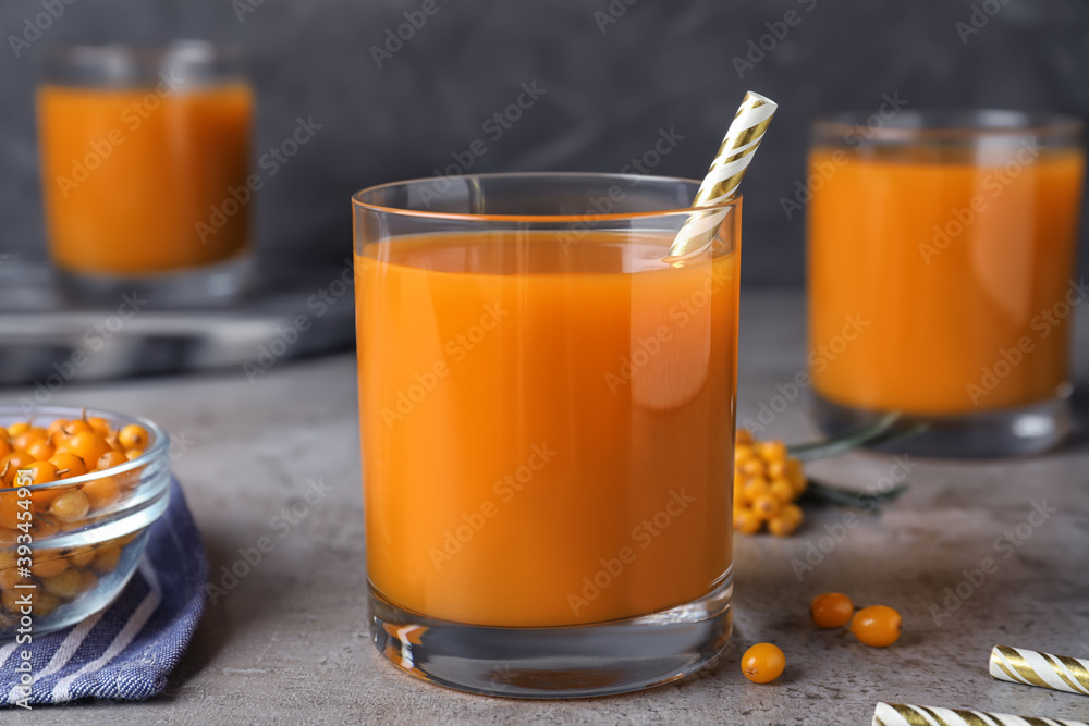 Delicious sea buckthorn juice with straw on grey table, closeup Delicious sea buckthorn juice with straw on grey table, closeup