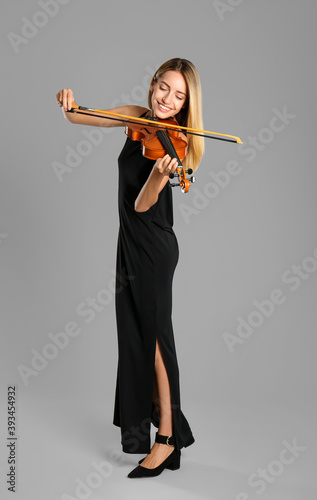 Canvas Print Beautiful woman playing violin on grey background