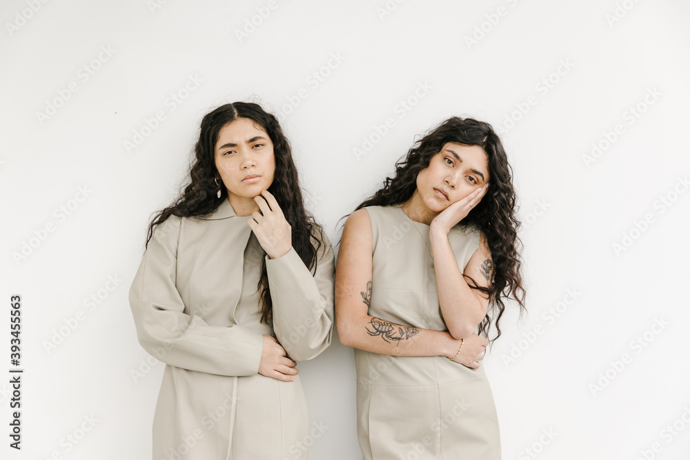 two women wearing matching outfits with white background and same body language two women wearing matching outfits with white background and same body language