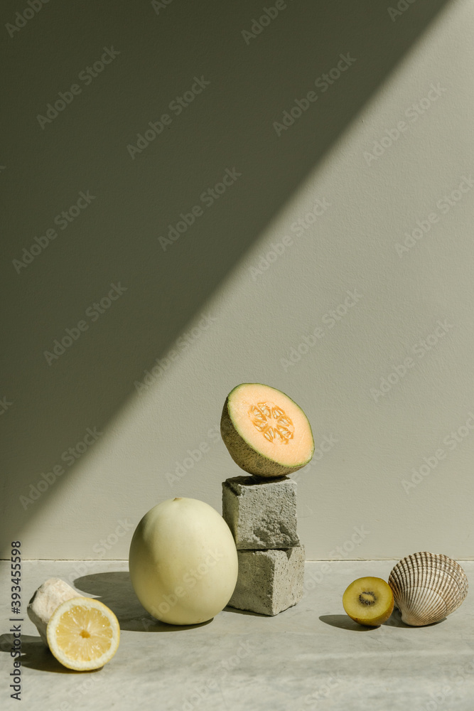 still life of melons and fruits in direct sunlight with diagonal shadow