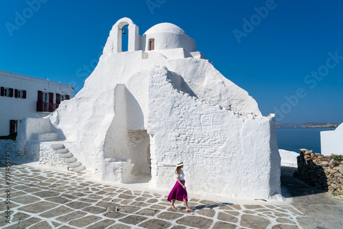 Asian woman walking by Church of Panagia Paraportiani in Mykonos, Greece photo