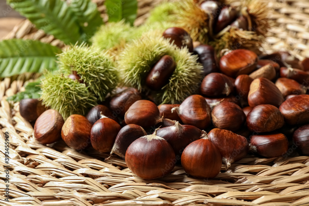 Fresh sweet edible chestnuts on wicker mat, closeup Fresh sweet edible chestnuts on wicker mat, closeup