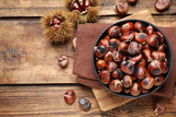 Delicious roasted edible chestnuts on wooden table, flat lay