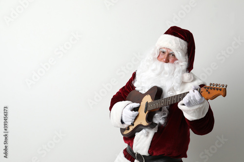 Santa Claus playing electric guitar on light background, space for text. Christmas music