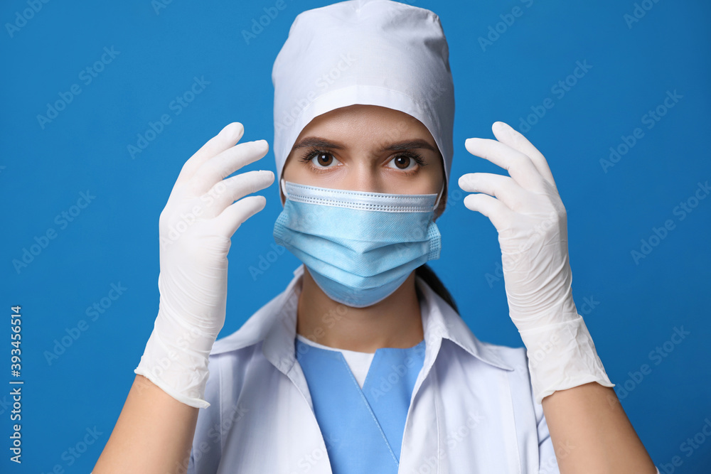Doctor in protective mask and medical gloves against blue background Doctor in protective mask and medical gloves against blue background