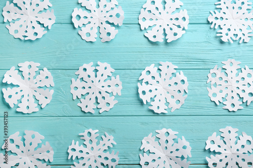 Fototapeta Naklejka Na Ścianę i Meble -  Many paper snowflakes on turquoise wooden background, flat lay