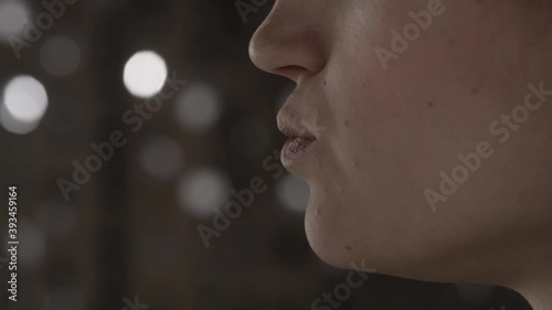 Side view positive european young beautiful girl brings a piece of meat to her mouth and chews it on a shiny background in cafe. European cuisine concept. Slow motion