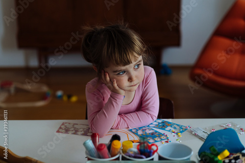 Bored kid sitting at table with toys
