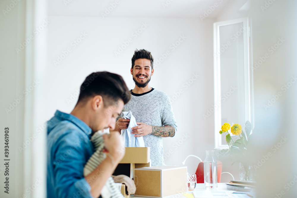 Happy ethnic boyfriends unpacking delivered clothes Happy ethnic boyfriends unpacking delivered clothes