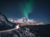 Northern lights and road leading to norwegian mountain peaks
