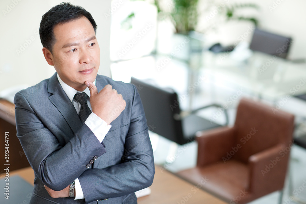 Mature businessman in office contemplating with hand on chin Mature businessman in office contemplating with hand on chin