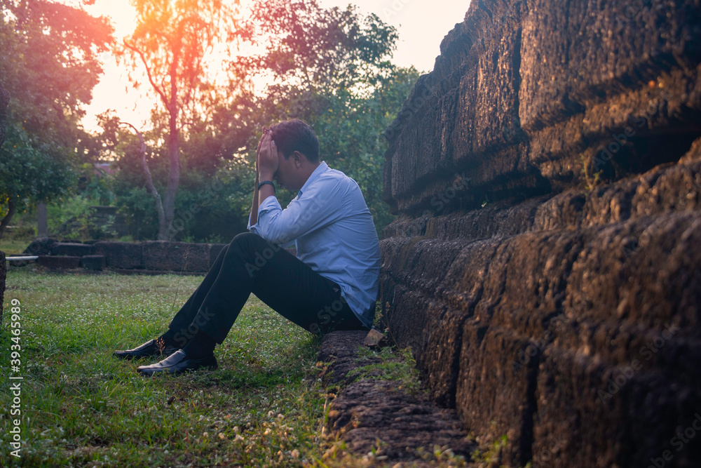 Asia you man sitting alone.He sitting alone beside old wall.man very sad and depressed.sad,alone,suicide,despair,sickness,photo health and disappointment concept.