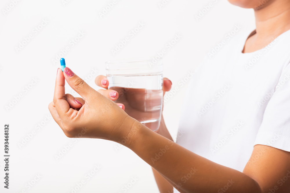 Closeup young Asian woman hold pill drugs in hand ready take medicines with a glass of water, studio shot isolated on white background, Healthcare and medical pharmacy concept Closeup young Asian woman hold pill drugs in hand ready take medicines with a glass of water, studio shot isolated on white background, Healthcare and medical pharmacy concept