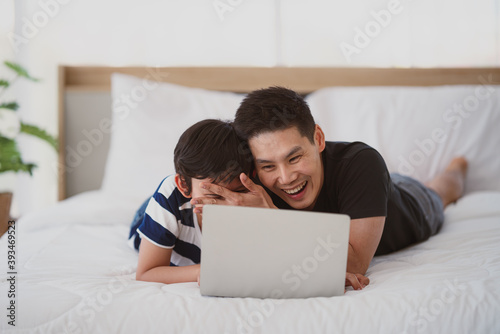 asian dad and son have good time using laptop computer together